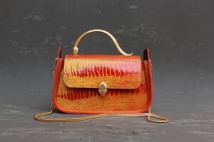 A unique, colorful handbag with a golden handle.