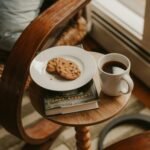 Coffee and cookies on a small table next to chair
