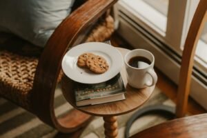 Coffee and cookies on a small table next to chair