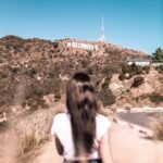 woman in white top standing beside road