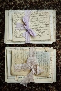 Stacked vintage handwritten letters tied with lace on a textured surface.