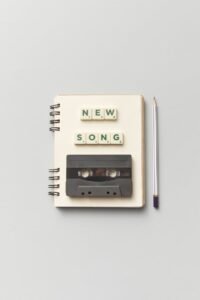 Close-up of a notebook with a vintage cassette and 'New Song' text, perfect for music lovers. Hilary Duff