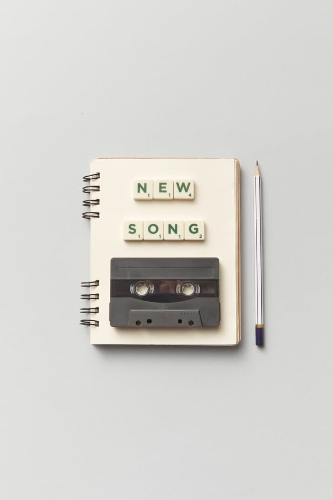 Close-up of a notebook with a vintage cassette and 'New Song' text, perfect for music lovers. Hilary Duff