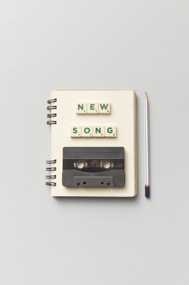 Close-up of a notebook with a vintage cassette and 'New Song' text, perfect for music lovers. Hilary Duff