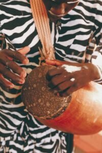 a woman in a zebra print shirt holding a drum, Nigeria